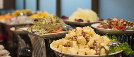 A buffet with various dishes including potato salad, coleslaw, and other salads.