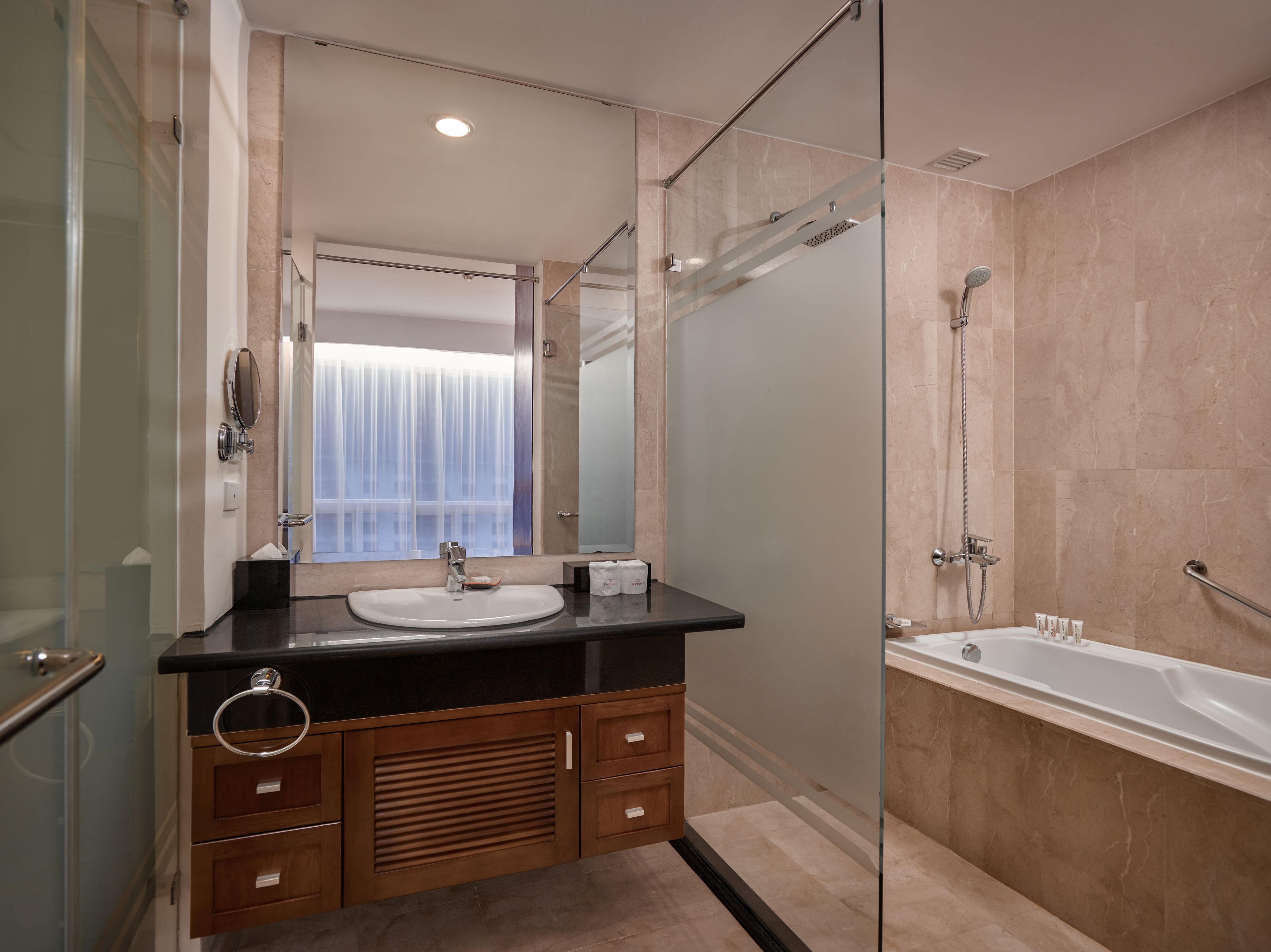 A modern bathroom with a glass shower enclosure, a bathtub, and a vanity with a sink and mirror.