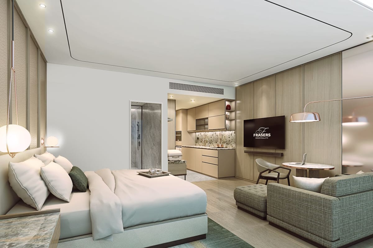 A modern hotel room with a bed, a seating area, a TV, and a kitchenette.