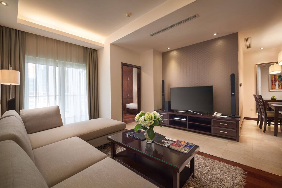 A modern living room with a sofa, coffee table, TV, and dining area.