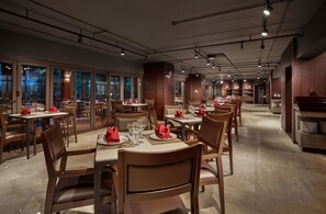 Un restaurante espacioso con varias mesas y sillas, ventanas amplias y un diseño de interiores moderno.