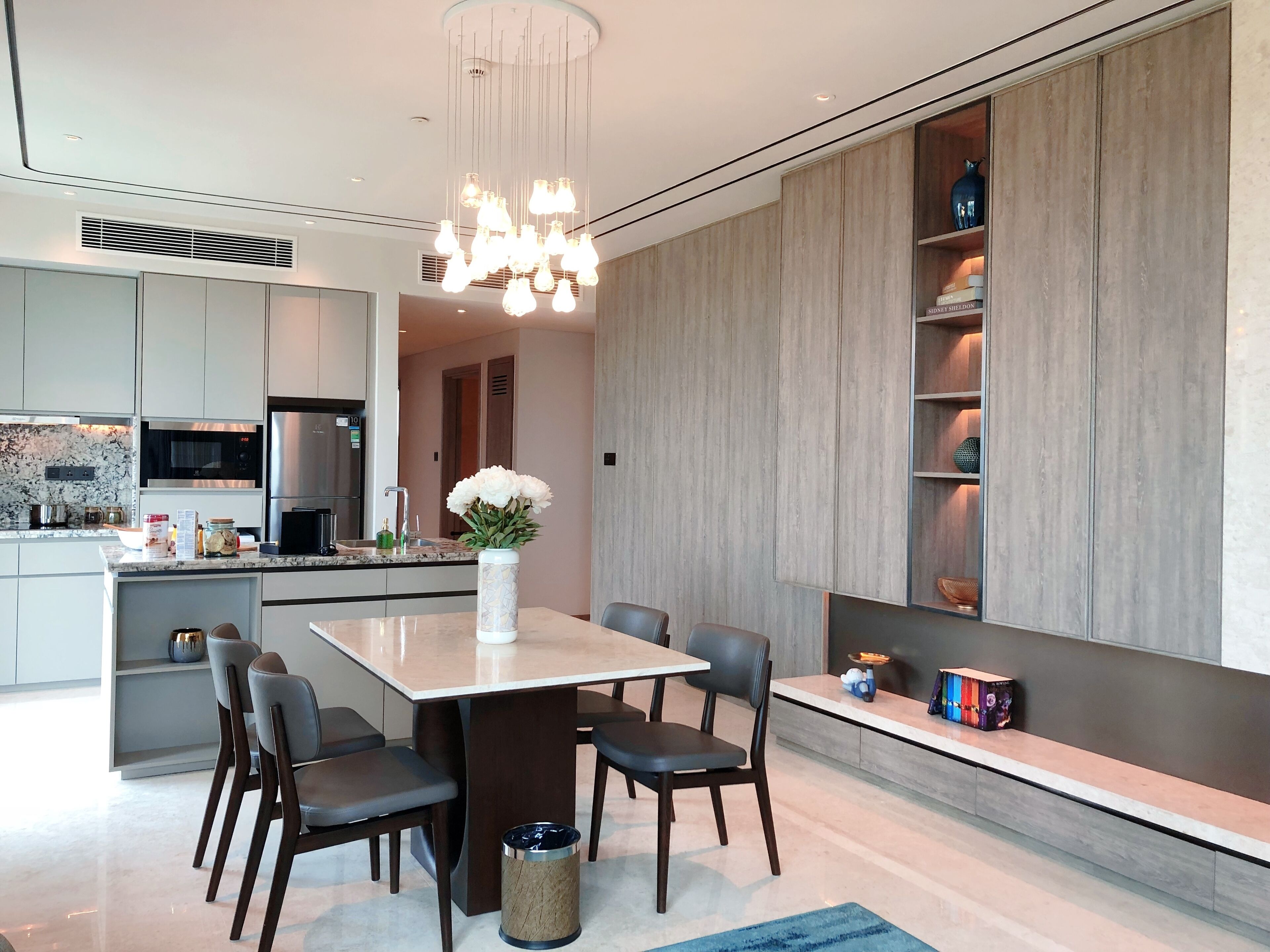A modern kitchen with a central island, built-in appliances, and a decorative light fixture.