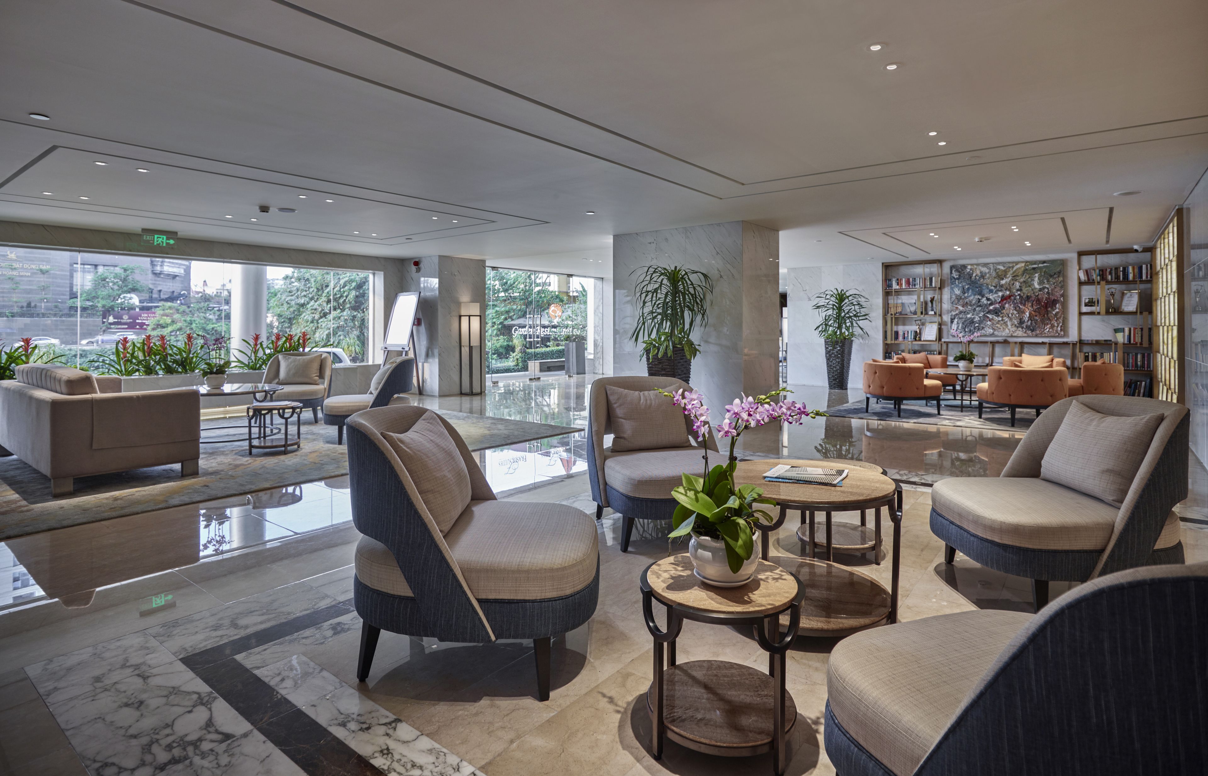 A modern lobby with comfortable seating, a large bookshelf, and a view of the outdoors.