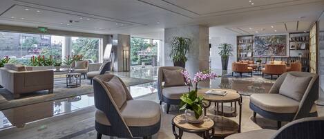 A modern lobby with comfortable seating, a large bookshelf, and a view of the outdoors.