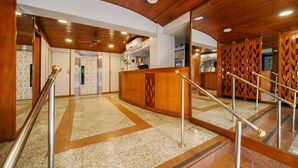 A lobby with a reception desk, a staircase with metal railings, and a patterned floor.