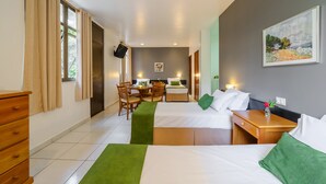 A hotel room with two beds, a dining area, and a TV.