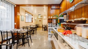 A restaurant with wooden paneling, a buffet area with fruits and beverages, and a dining area with tables and chairs.