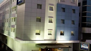 Um edifício de hotel moderno com uma placa que diz "Aditya Hometel" e "Sarovar Hotel".