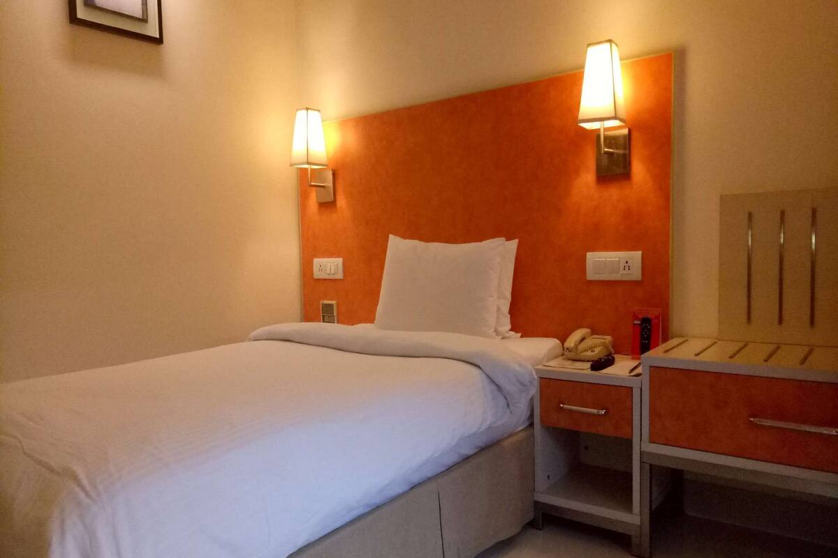 Een hotelkamer met een bed, nachtkastje en een bijzettafeltje met lamp.