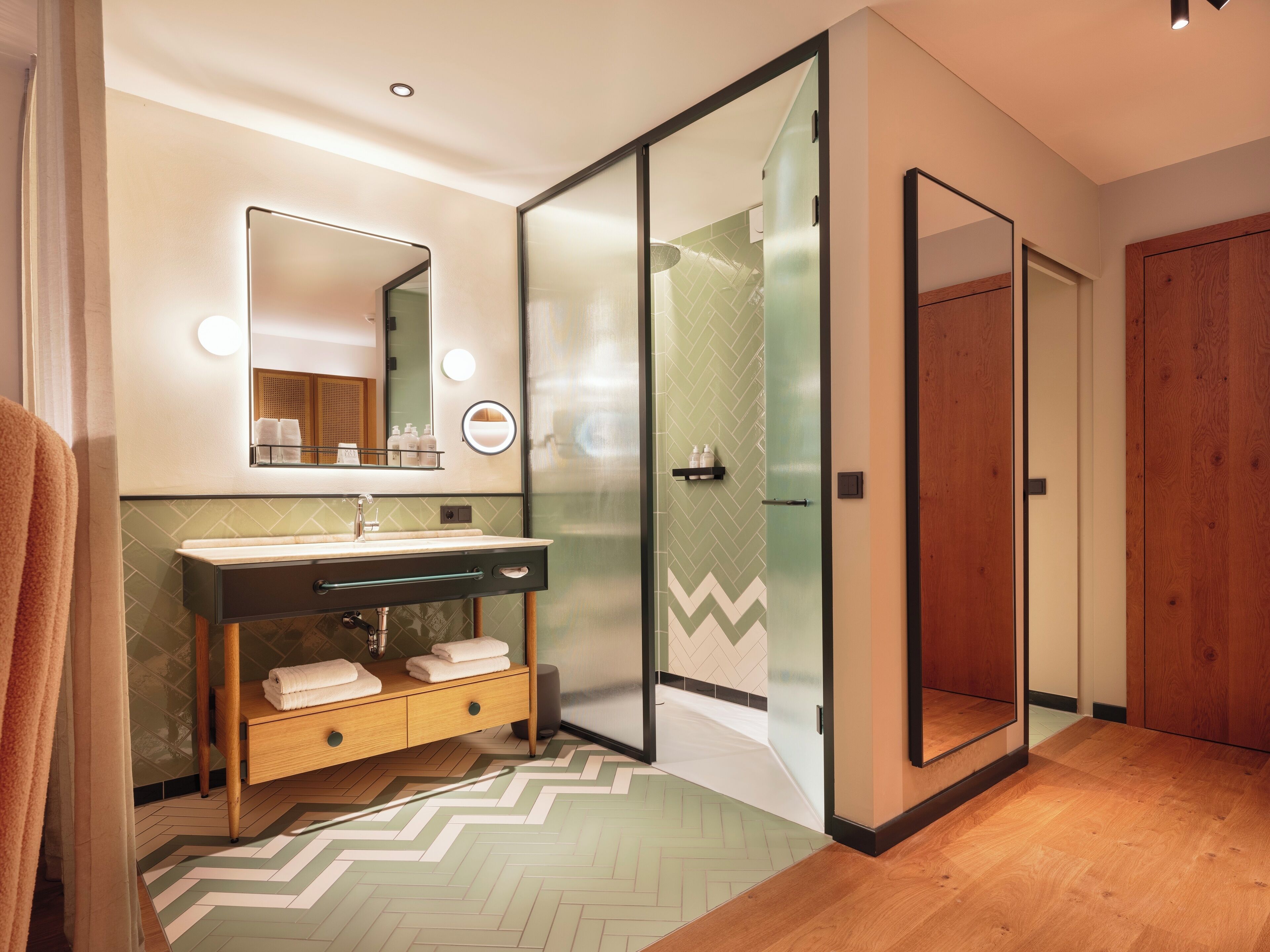 A modern bathroom with a vanity, mirror, and shower area.