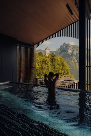 Eine Person in einer Hot Tub mit Blick auf einen Berg und einen Turm.