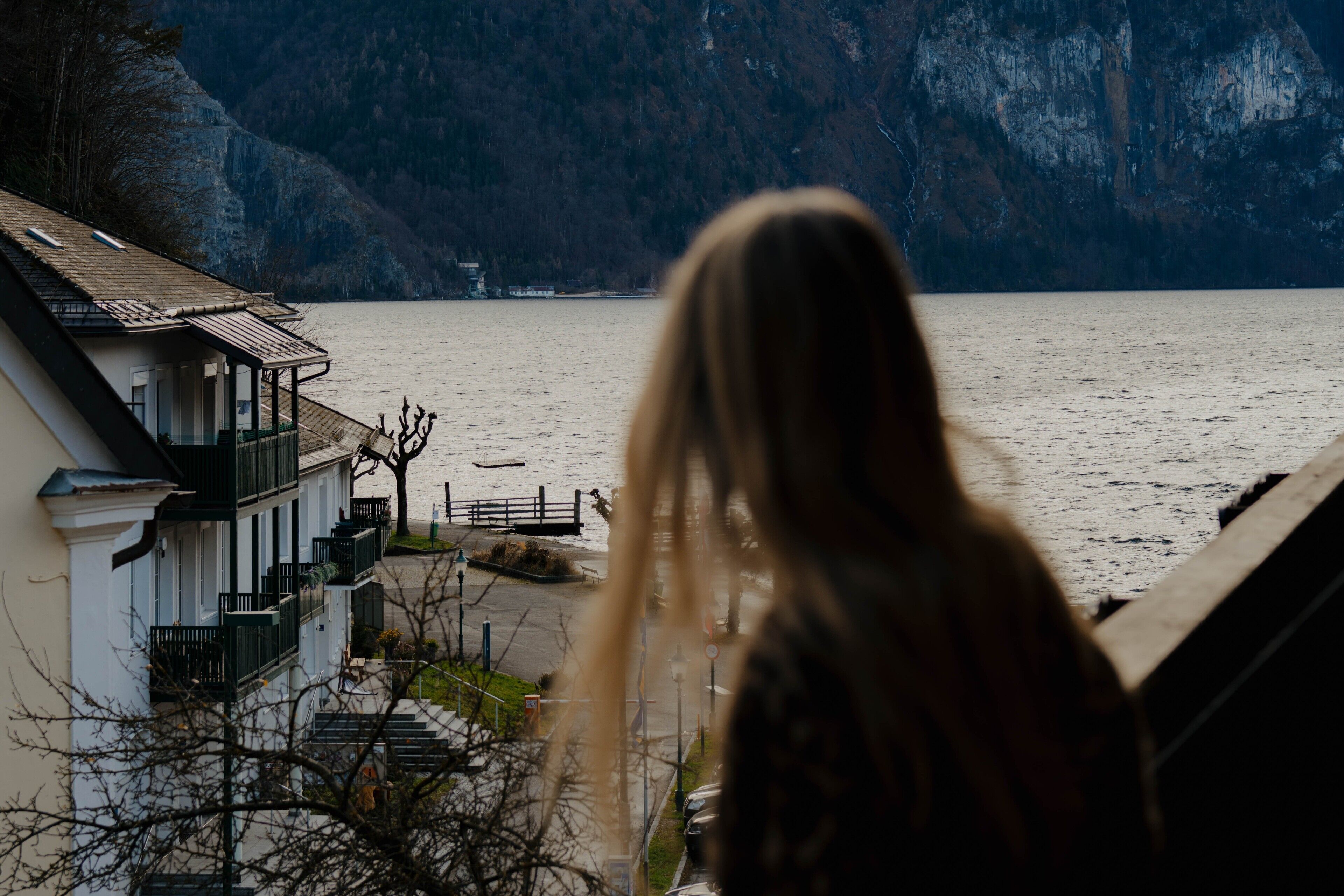 Una persona mirando un lago con edificios al frente.
