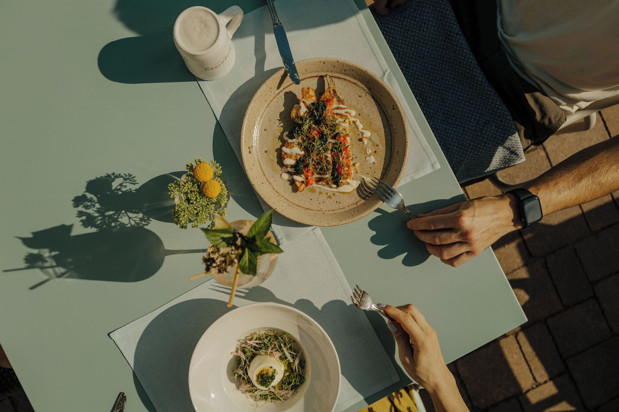 A dining table with a plate of food, a cup, and a fork.