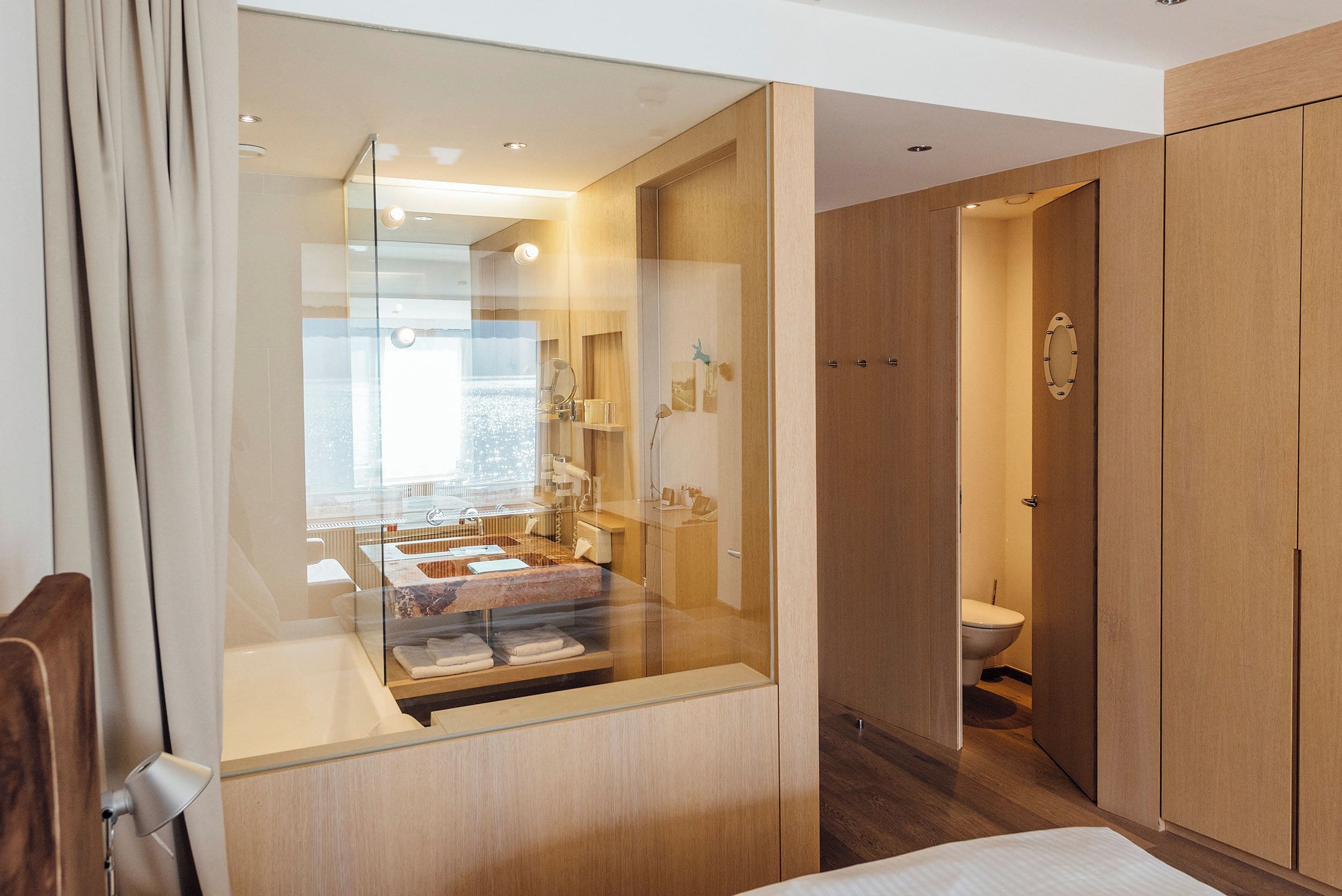 A modern bathroom with a glass-enclosed shower, a toilet, and wooden cabinetry.
