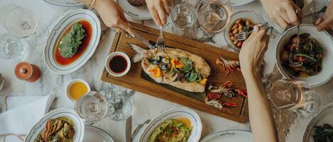 A dining table with multiple plates of food, glasses of water, and cutlery.