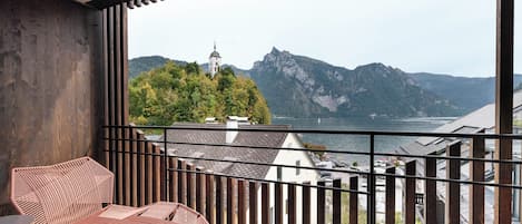 Un balcón con vistas a una montaña, un lago y una torre de iglesia.