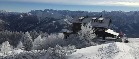 Un lodge en la montaña cubierto de nieve, con una vista despejada de los picos circundantes.