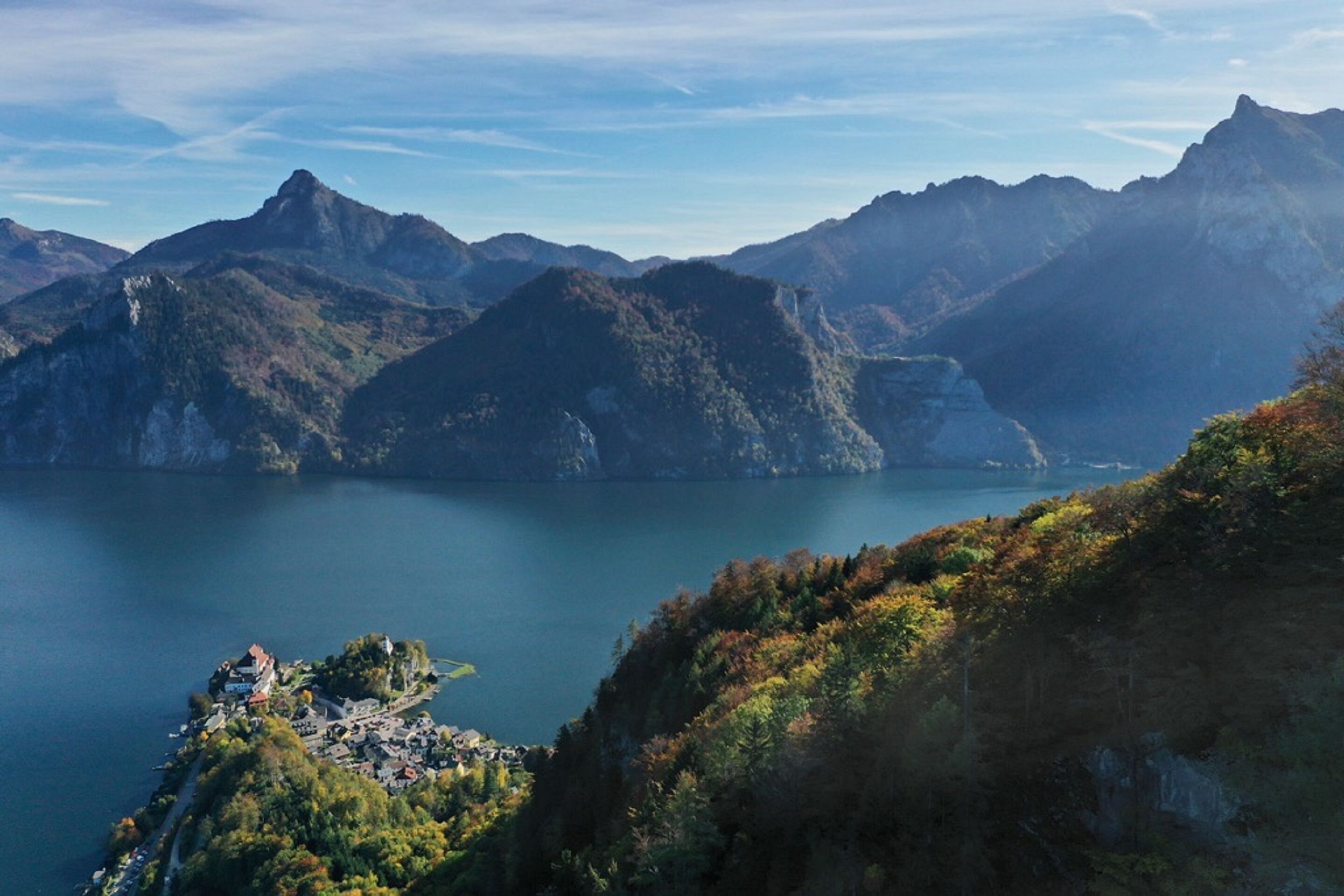 Un paisaje montañoso con un lago y un pequeño asentamiento.