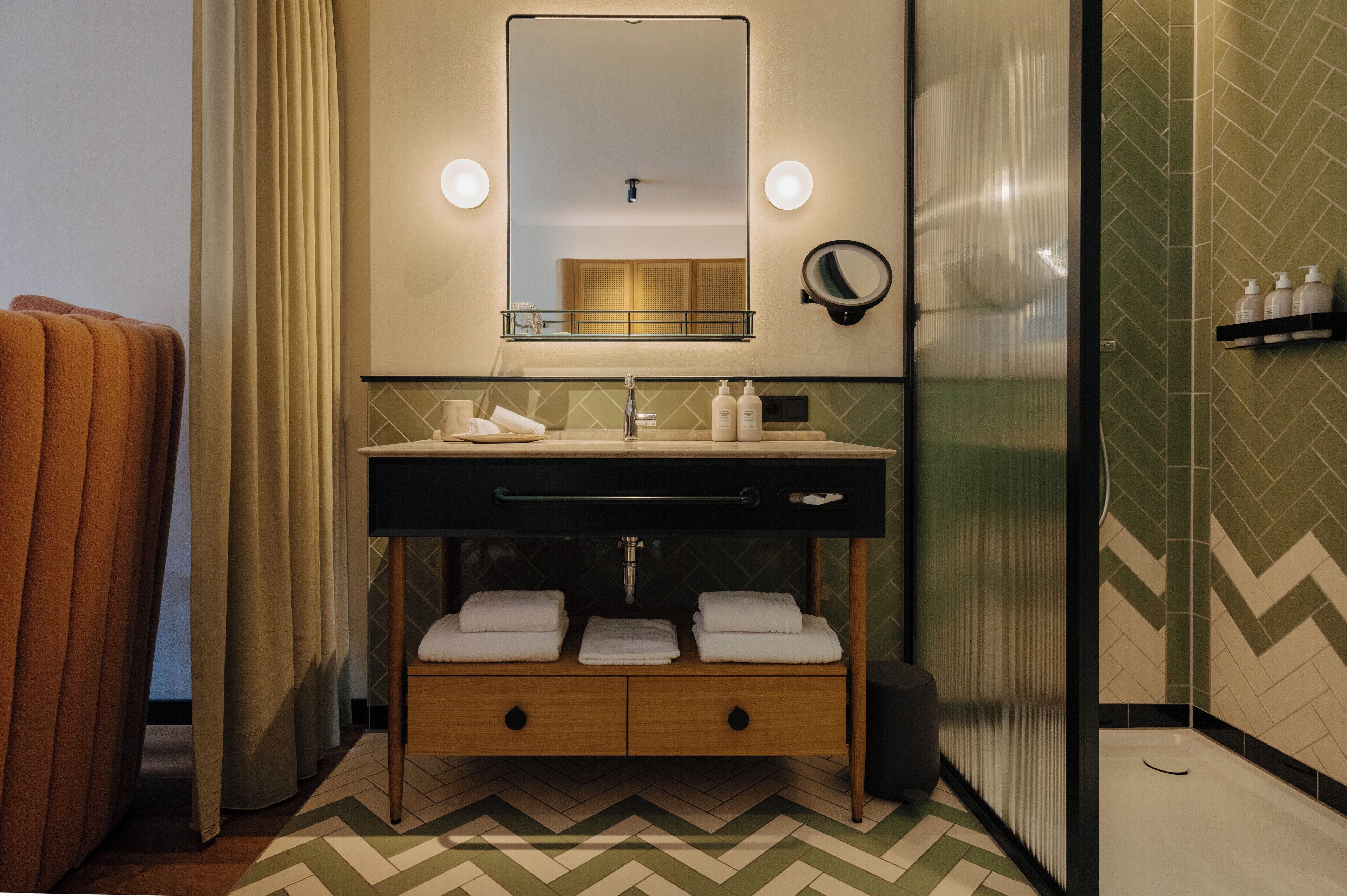 A modern bathroom with a large mirror, a sink with a towel rack, and a shower area.