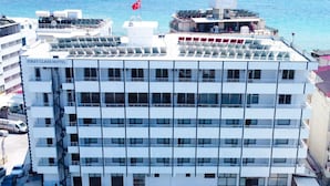 Et hotel med flere etager, et poolområde, udendørs siddepladser og havudsigt.