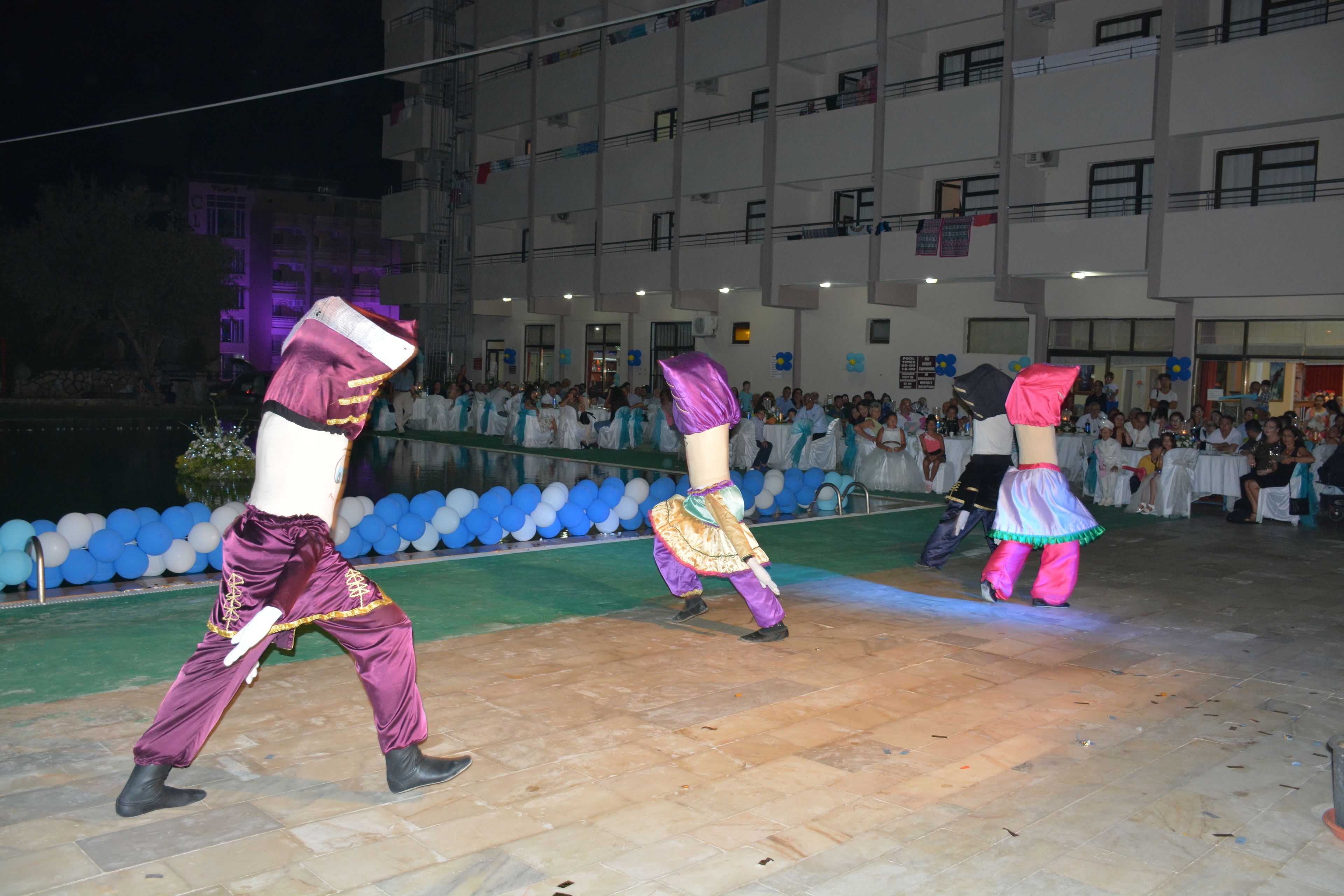 A group of people performing a dance in an outdoor setting with a crowd watching.