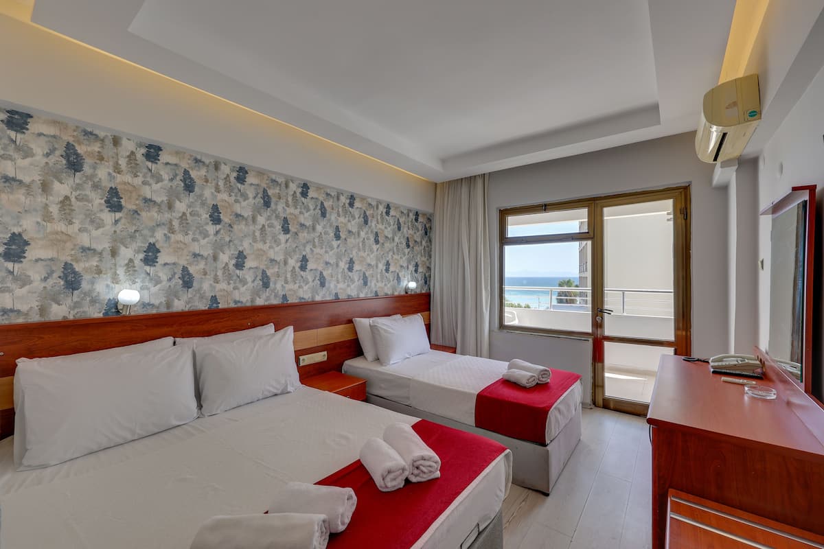 A hotel room with two beds, a wooden headboard, a large window with a view, and a desk with a telephone.