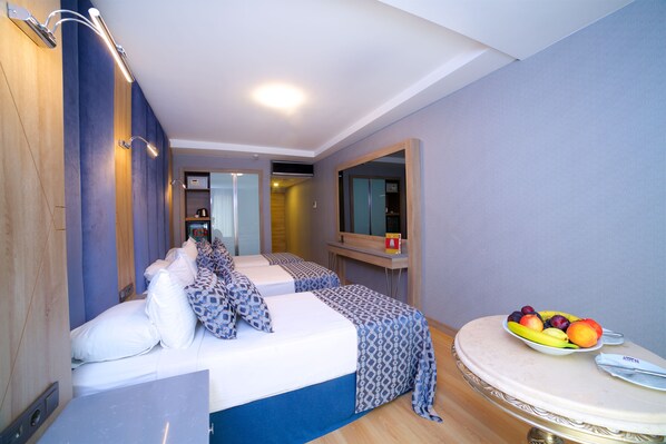 A modern hotel room with a bed, bedside table, and a fruit bowl.