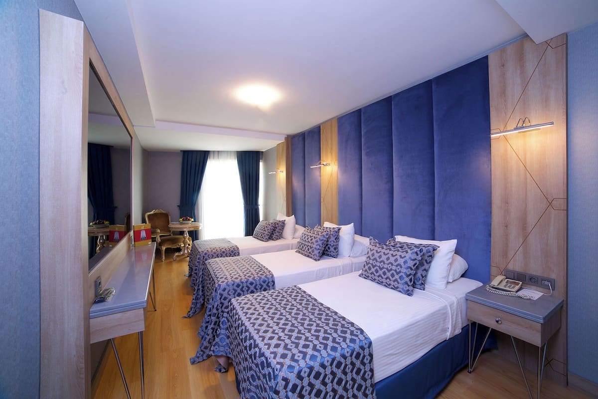 A hotel room with two beds, a desk, a chair, and a mirror.