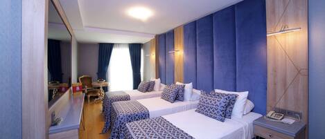 A hotel room with two beds, a desk, a chair, and a mirror.