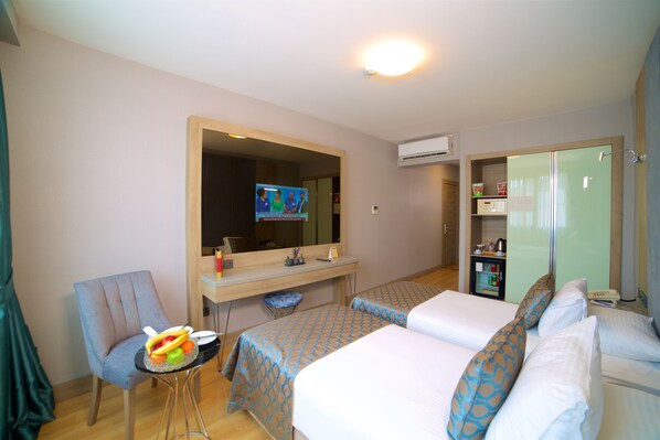 Habitación de hotel con dos camas, un escritorio, una silla y una mesita con fruteros.