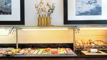 A buffet with various food items and framed artwork on the wall.