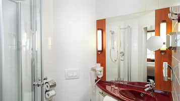 Ein modernes Badezimmer mit einer Duschkabine aus Glas, einem roten Waschbecken, einem großen Spiegel und einem Handtuchhalter.