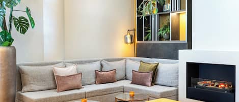 A modern living room with a grey sofa, yellow ottoman, and a fireplace.