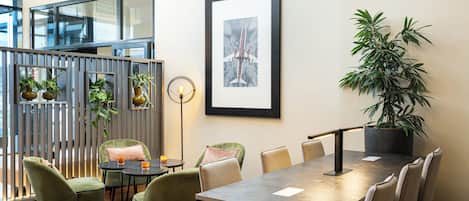 Une salle de réunion moderne, dotée d’une longue table, de chaises confortables, de plantes en pot et d’une œuvre d’art encadrée au mur.