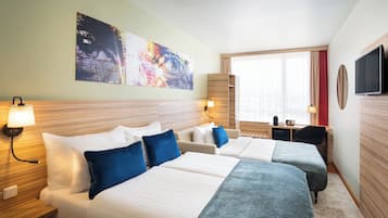 Habitación de hotel con dos camas, un escritorio, un televisor y un cuadro abstracto grande en la pared.