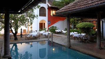 Dine al fresco amidst lush greenery and a serene pool view.