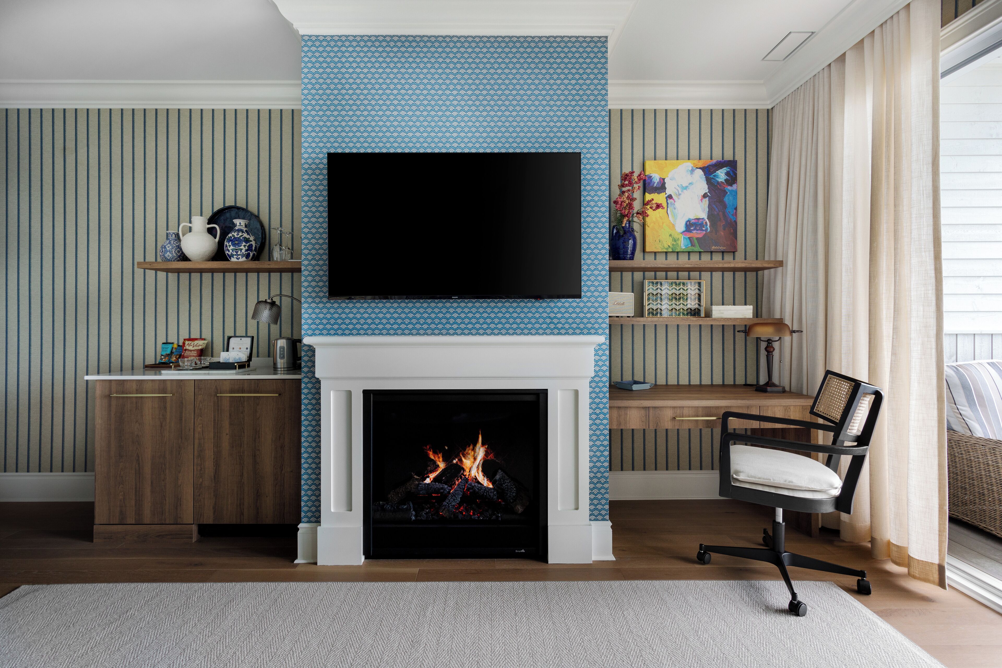 A living room with a fireplace, a flat-screen TV mounted above it, and a comfortable seating area with a chair and a sofa.