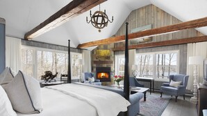 Un dormitorio amplio con una cama grande, una chimenea y vistas al exterior.