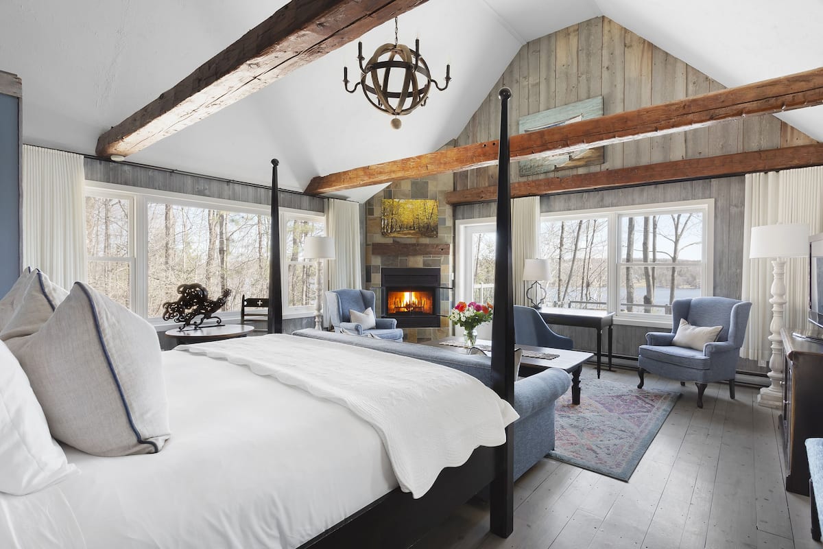 Um quarto espaçoso com uma cama grande, uma lareira e vista para o exterior.