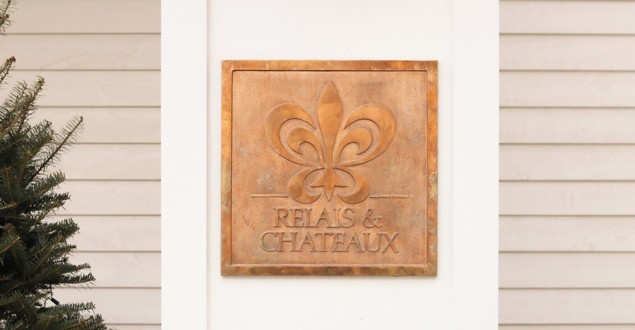 A plaque with a fleur-de-lis and the words "RELAIS & CHATEAUX" mounted on a wall.