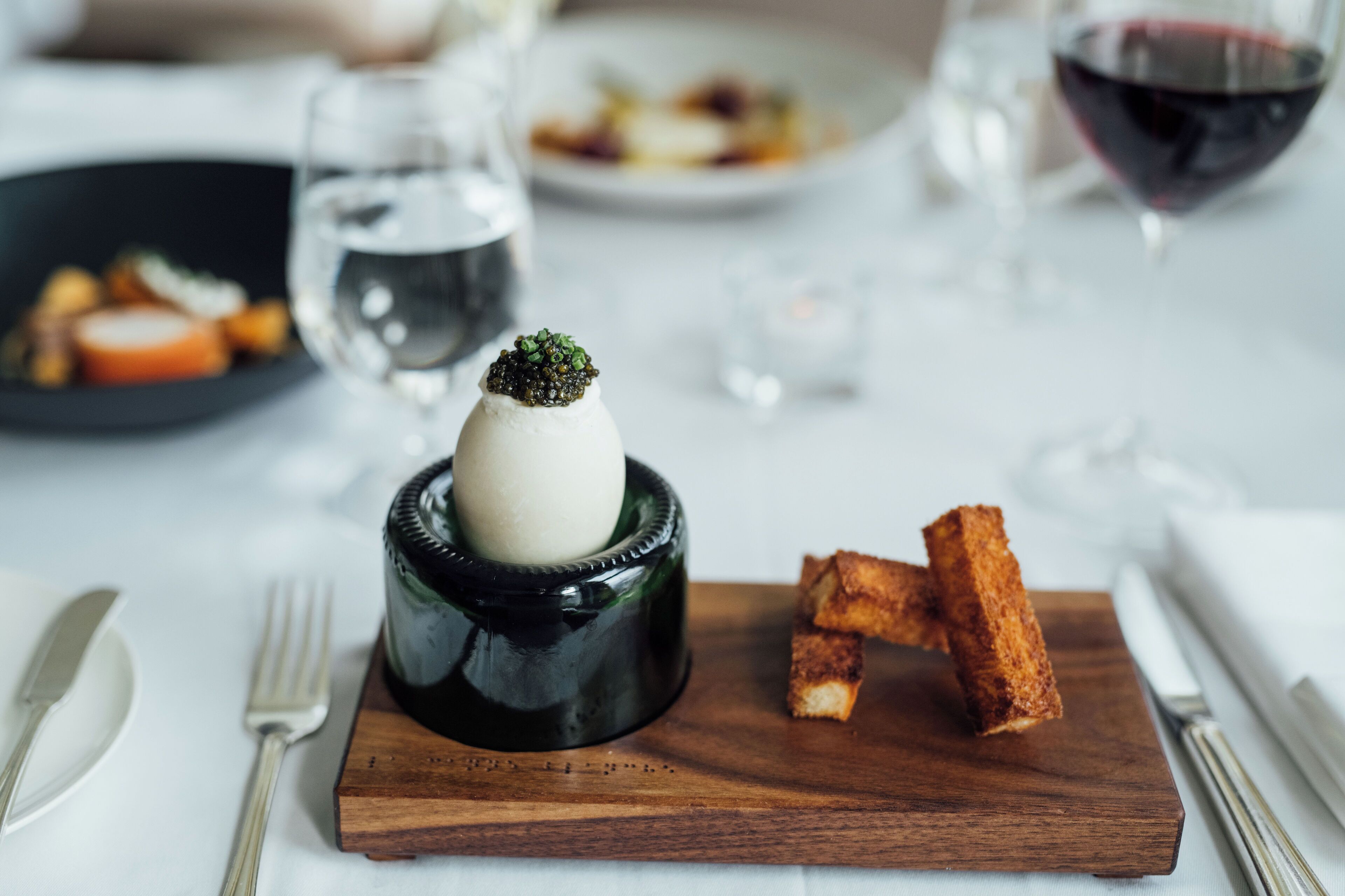 A dining table with a plate of food, a glass of water, and a glass of red wine.