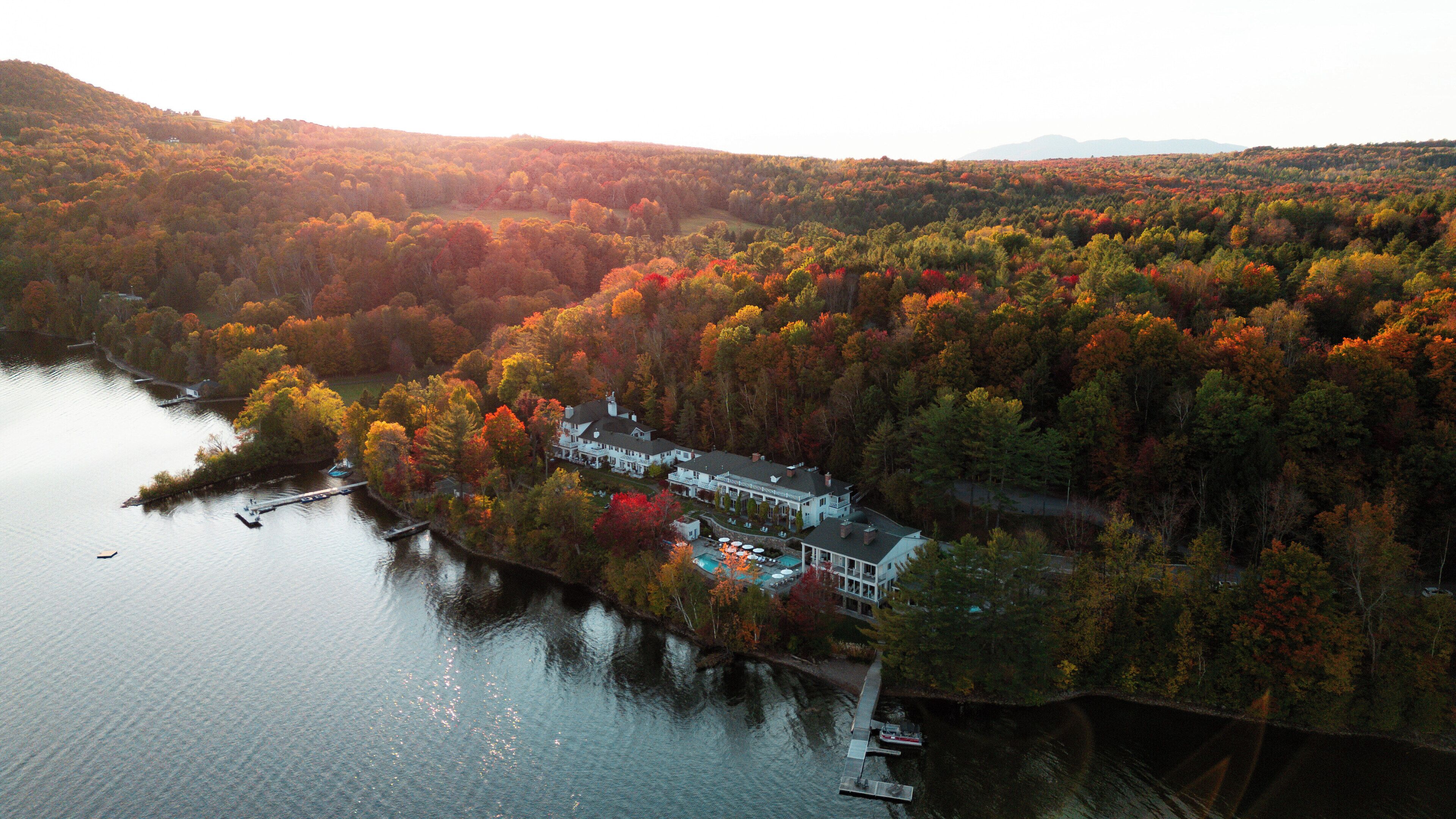 Vue aérienne d’une propriété au bord du lac, avec une grande maison, un quai et une piscine.