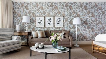 A living room with patterned wallpaper, a sofa, a coffee table with decorative items, and two lamps.