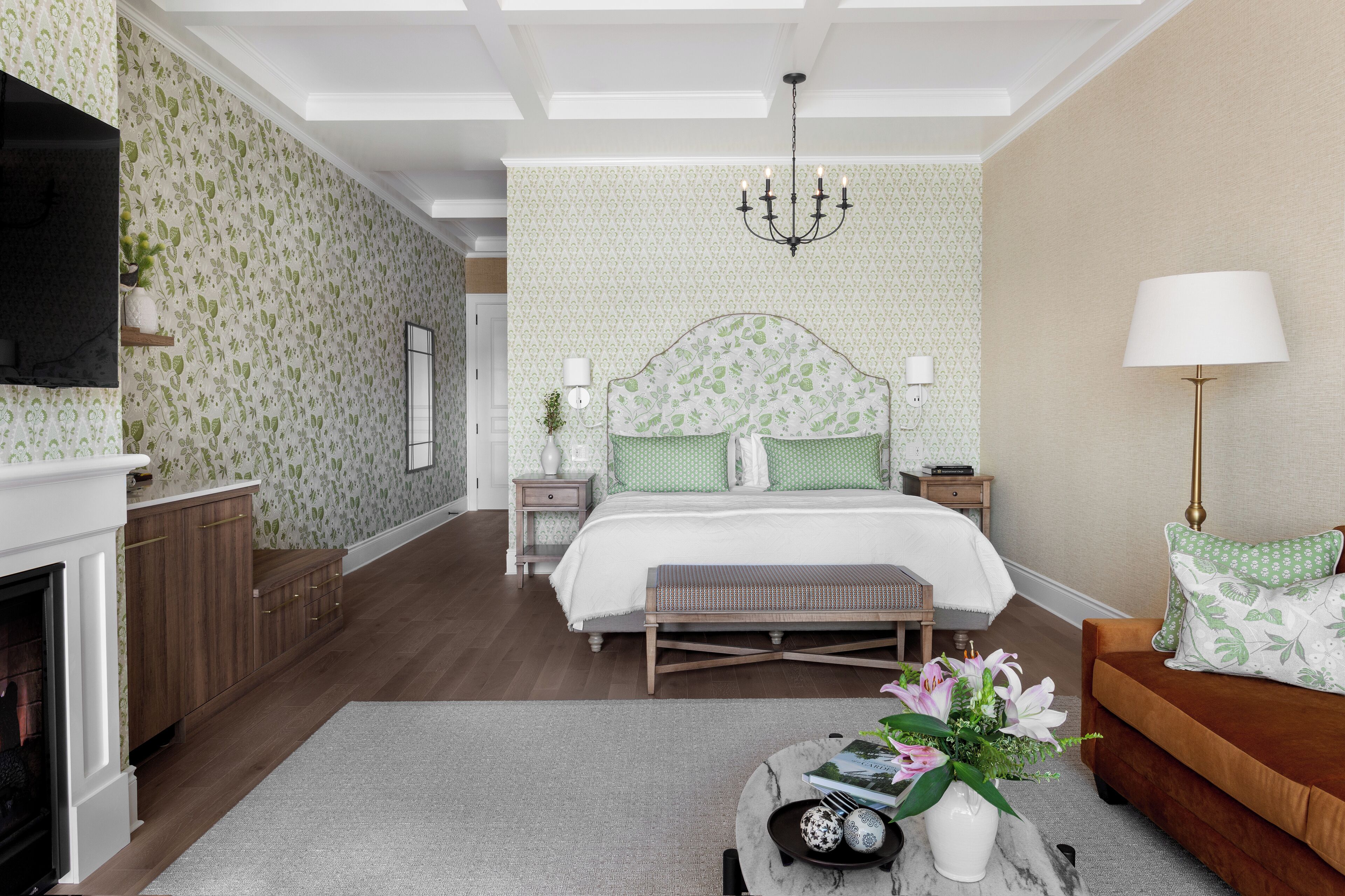 Une chambre à coucher comprenant un lit, des tables de chevet, une commode, une lampe, une cheminée et un canapé.
