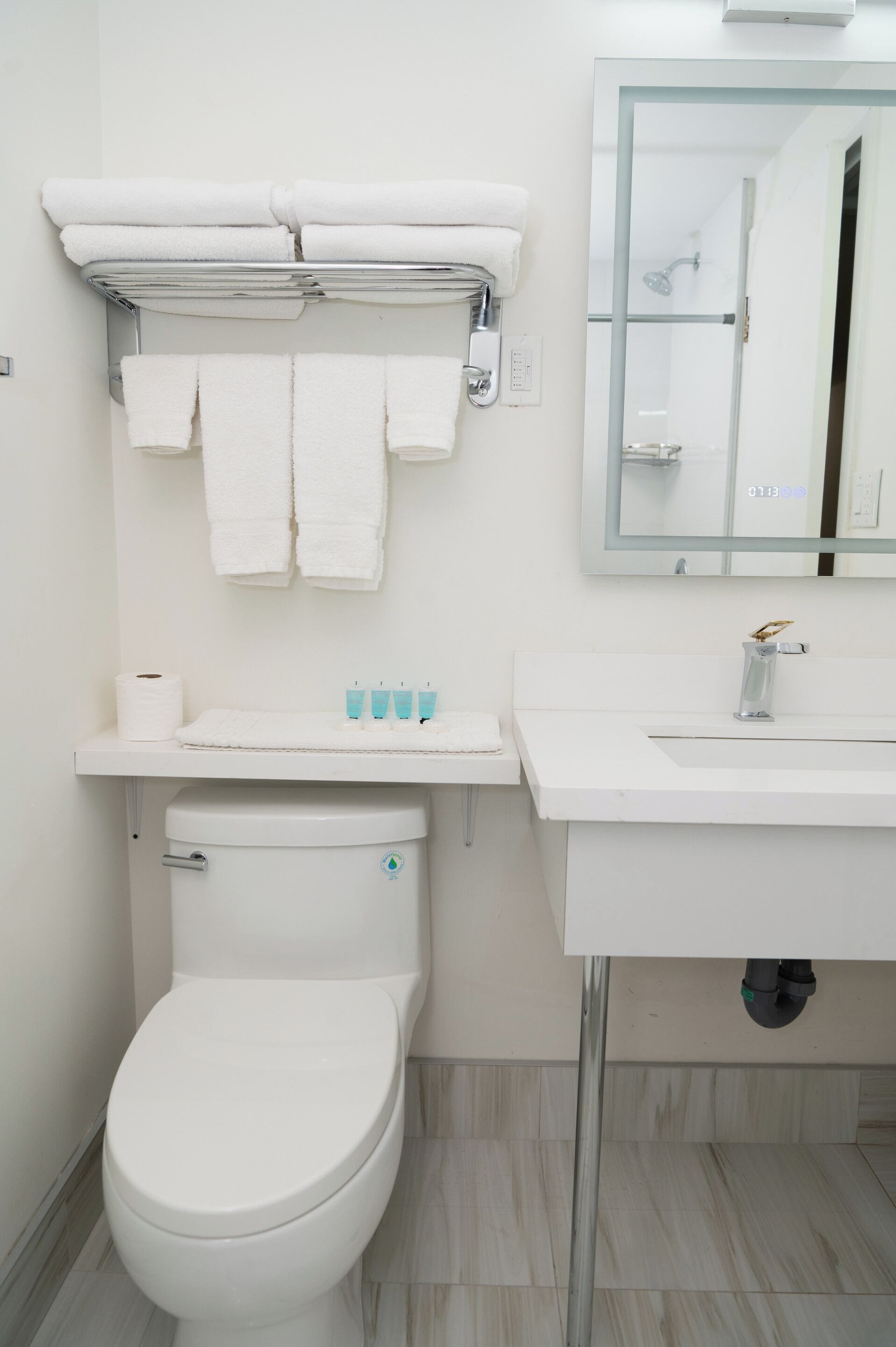 A modern bathroom with a toilet, sink, and a towel rack with folded towels.