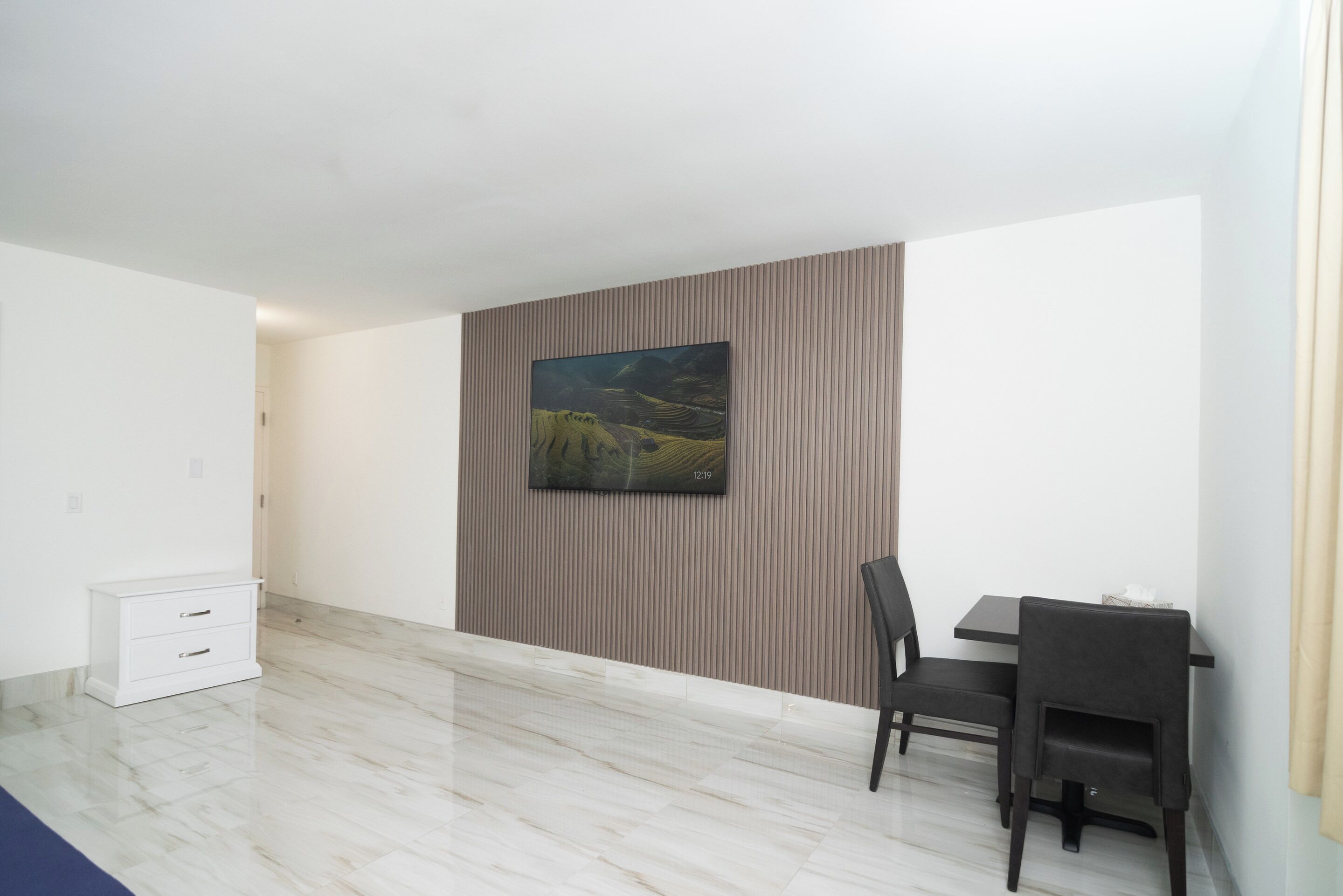 Een moderne woonkamer met een groot schilderij aan de muur, een eettafel met stoelen en een witte kast.