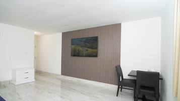 Een moderne woonkamer met een groot schilderij aan de muur, een eettafel met stoelen en een witte kast.