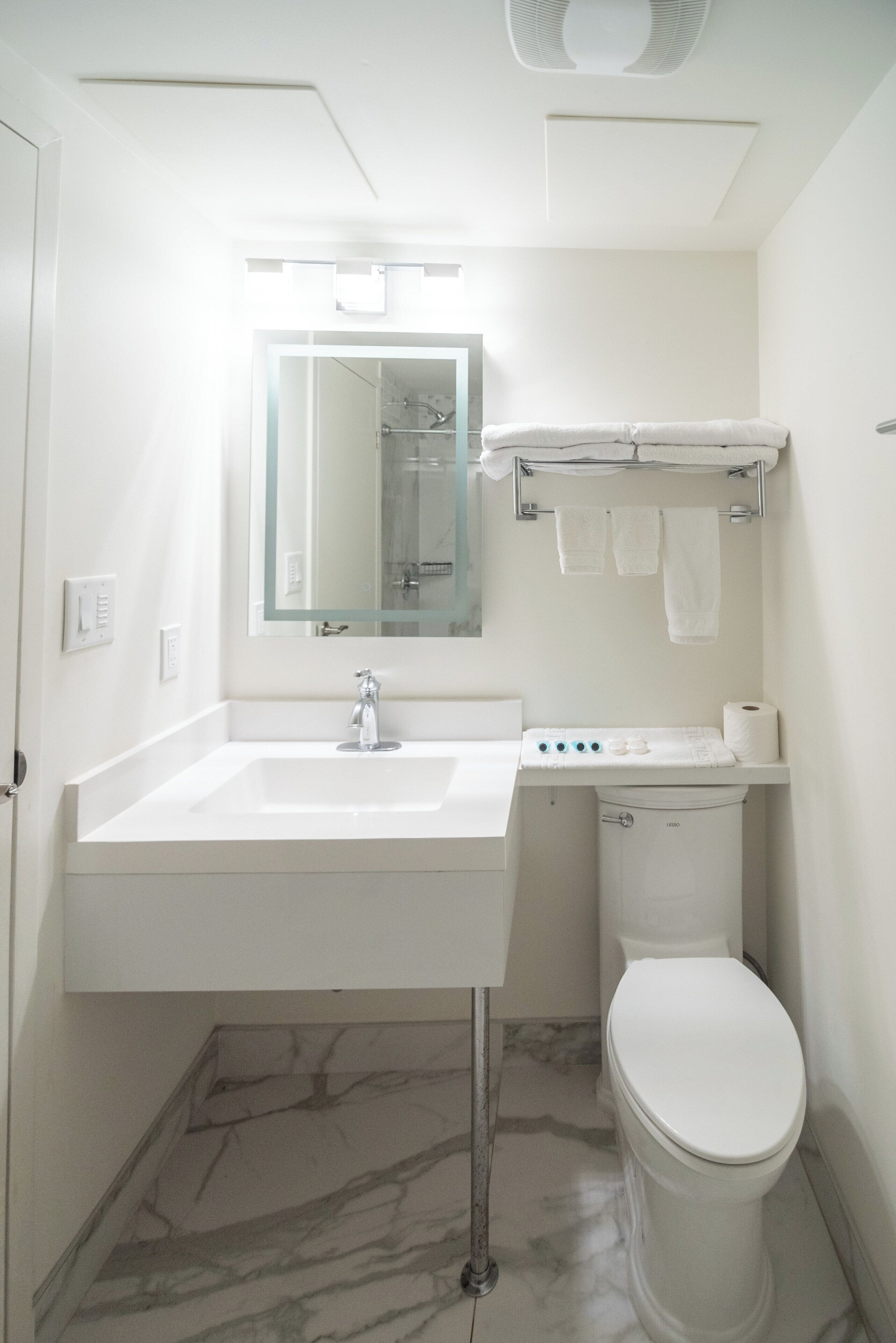 A bathroom with a white sink, mirror, and toilet.