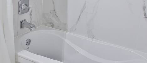 A modern bathroom with a freestanding bathtub, a showerhead, and a towel rack.