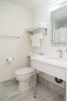 A modern bathroom with a white toilet, a sink with a mirror, and a towel rack.